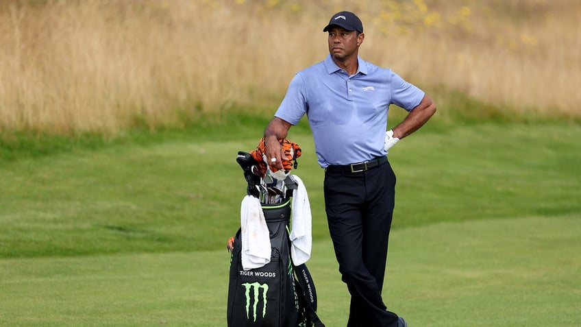 Tiger Woods leans on his bag