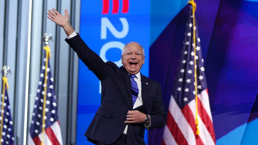 Gov. Tim Walz on stage at DNC, flags behind him