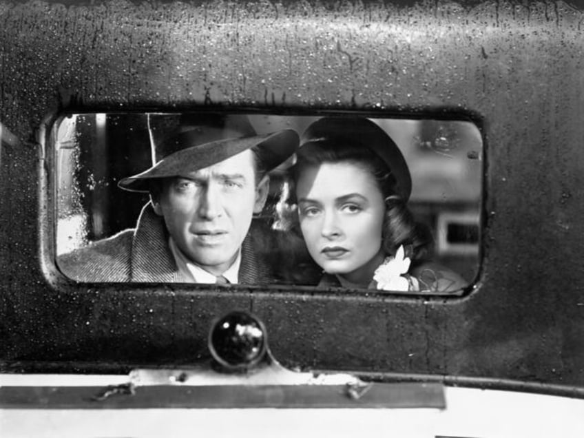 James Stewart and Donna Reed look out of the back window of vintage car in a scene from th