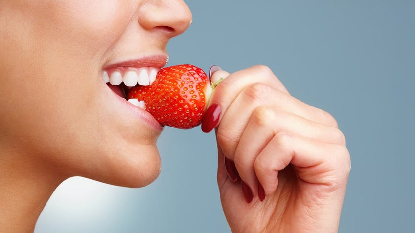 woman bites into a strawberry