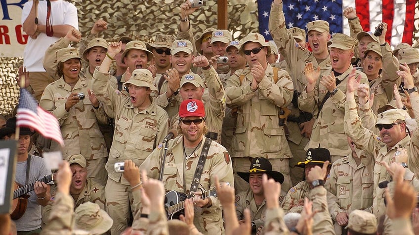 Toby Keith wears a red hat while performing for the Army.