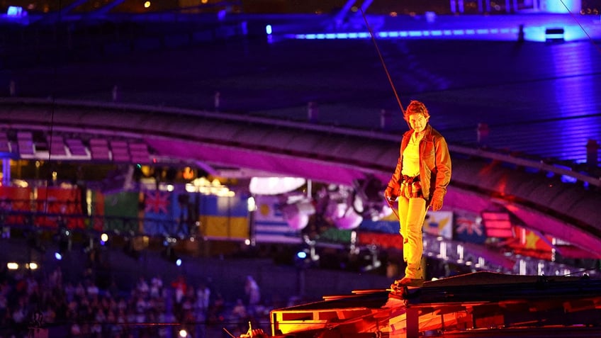 Tom Cruise suits up in harness for big jump.