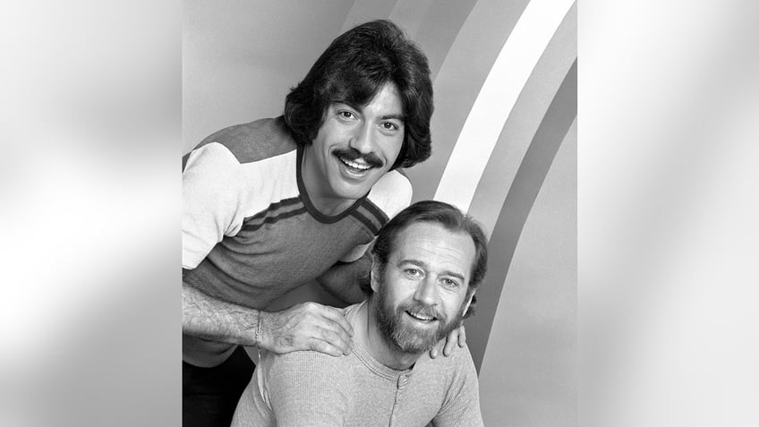 Tony Orlando standing behind George Carlin with his hands on Carlins shoulders