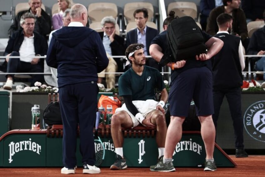 Lorenzo Musetti (C) briefly received treatment on his left thigh before being forced to re