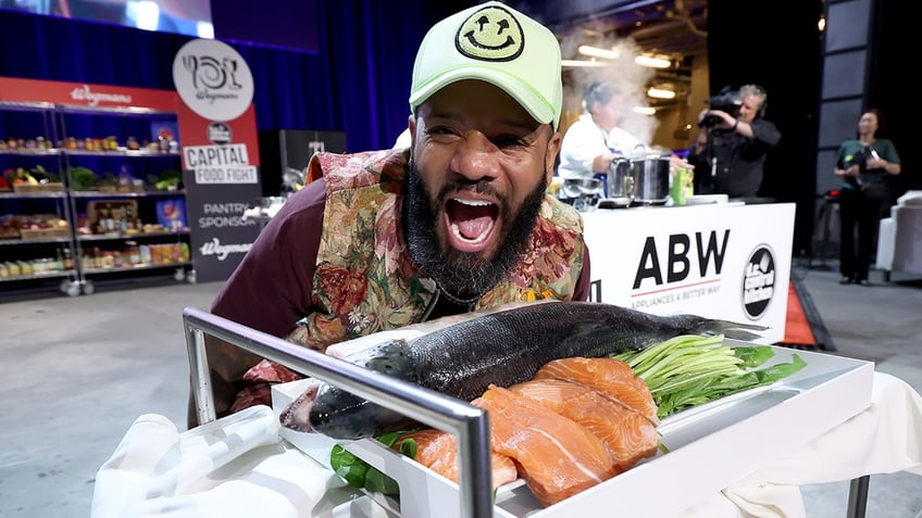 Justin Sutherland wide mouth smiles in front of a dead fish