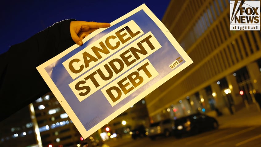 An activist holds a sign that reads "Cancel Student Debt."