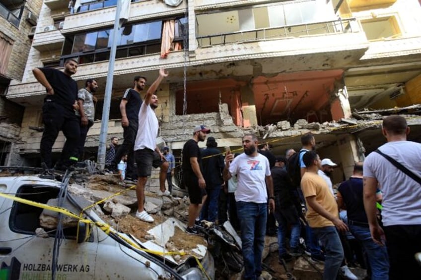 People in Hezbollah's southern Beirut stronghold gather in front of a building damaged in