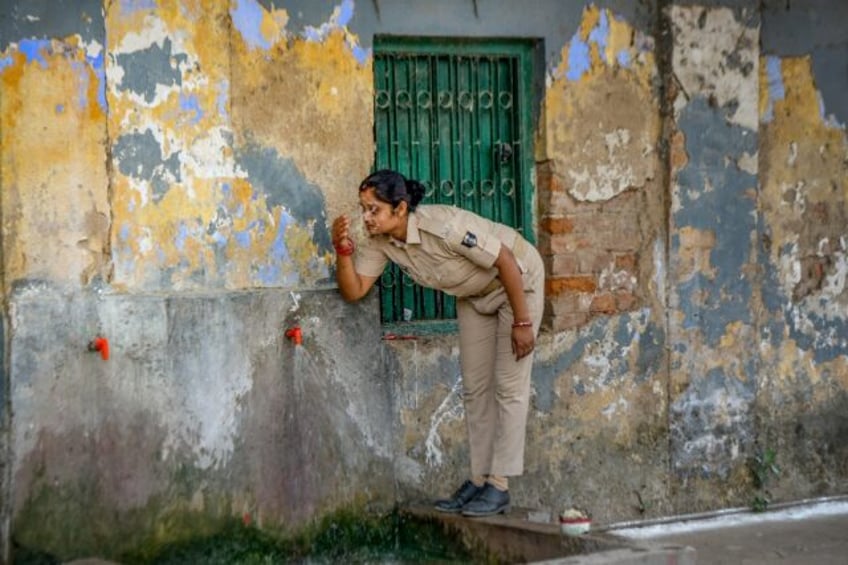 A police officer sprinkles water on her face: swathes of India are in the grip of a deadly