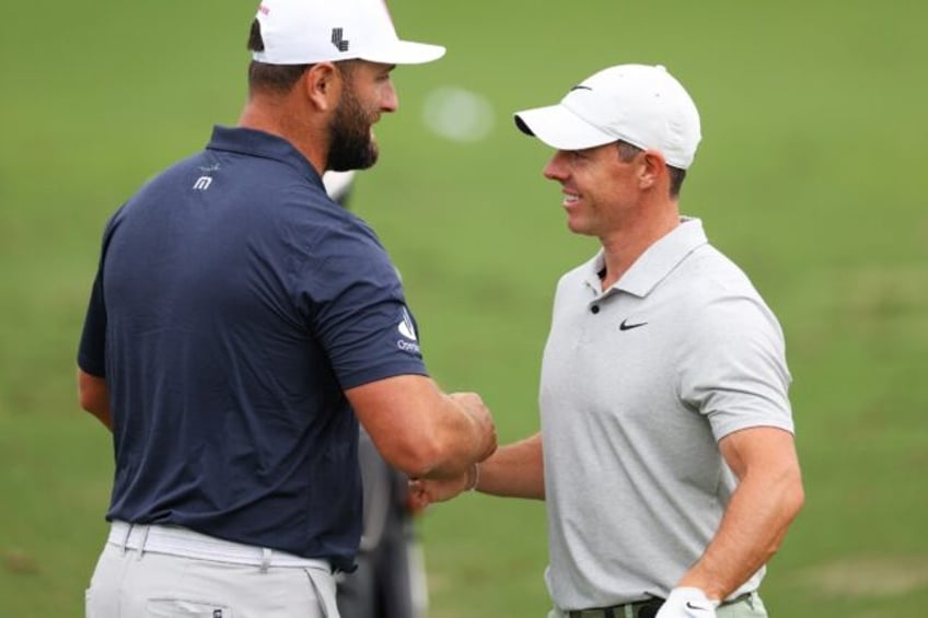 Defending champion Jon Rahm of Spain, left, greets world number two Rory McIlroy of Northe