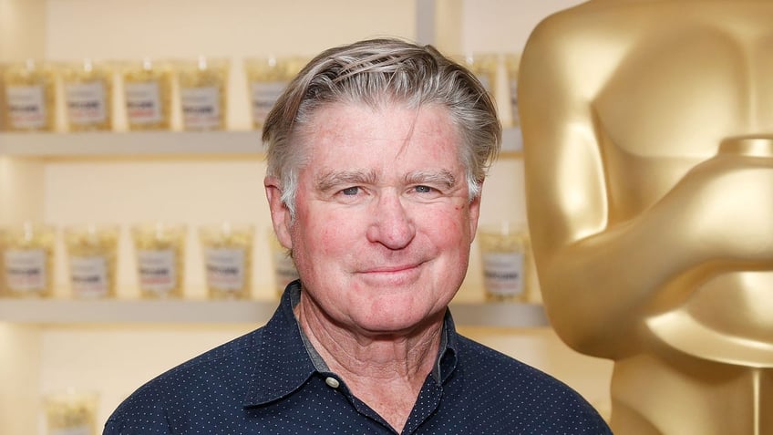 Treat Williams smiling near Oscar statue