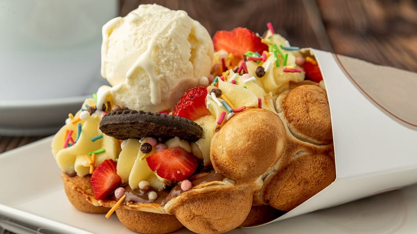 Hong kong or bubble waffle with ice cream, fruits, chocolate sauce and colorful candy.