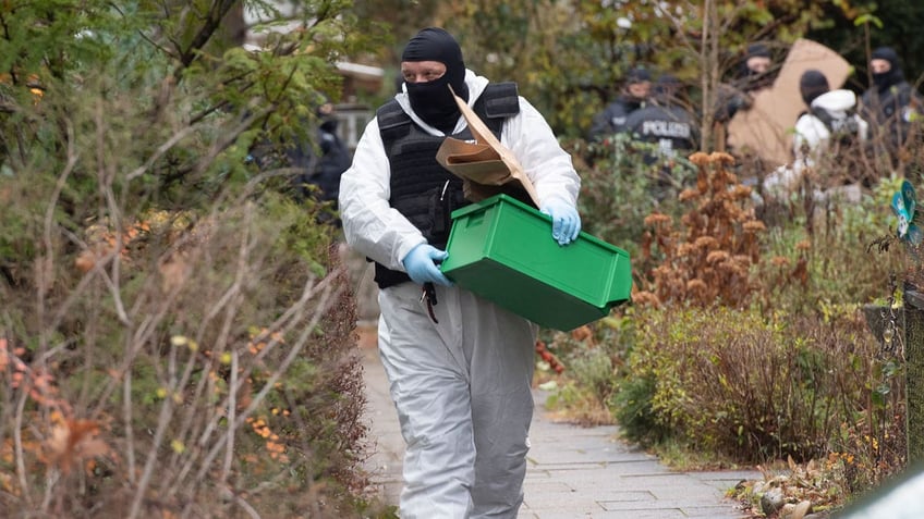 A police officer carries a plastic box during a raid against so-called 'Reich citizens' in Berlin, Germany