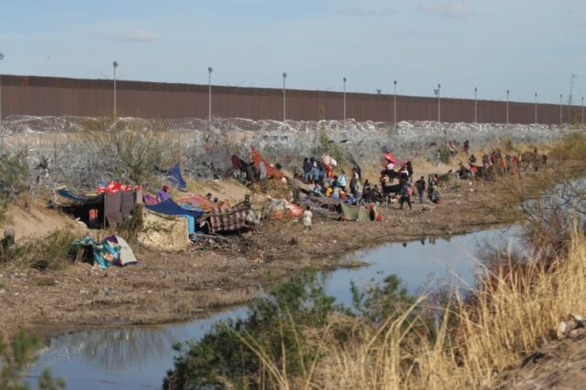 Migrants on the Mexican side of the border wait to cross into the United States at a point