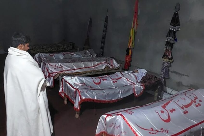 A man stands before the bodies of some of those killed in the sectarian clashes that have