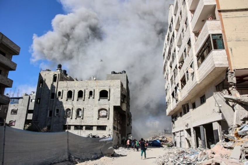 Palestinians in Gaza City watch as smoke rises from a building hit by a strike after an Is