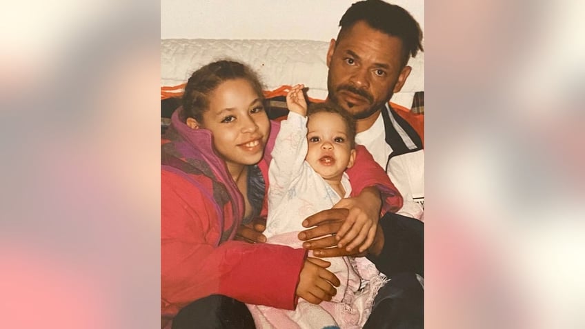 Madison McGhee holding her baby sister as her father J.C. looks ahead.