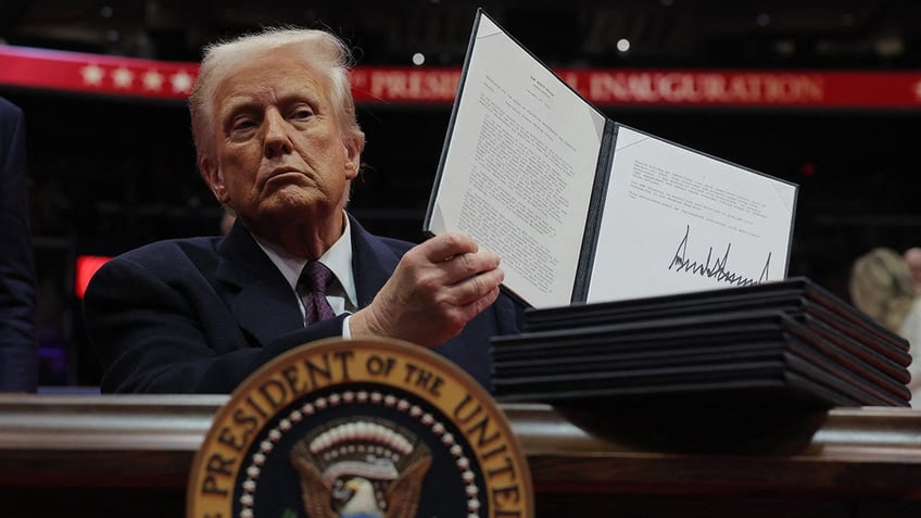 U.S. President Donald Trump shows his signature on an executive order