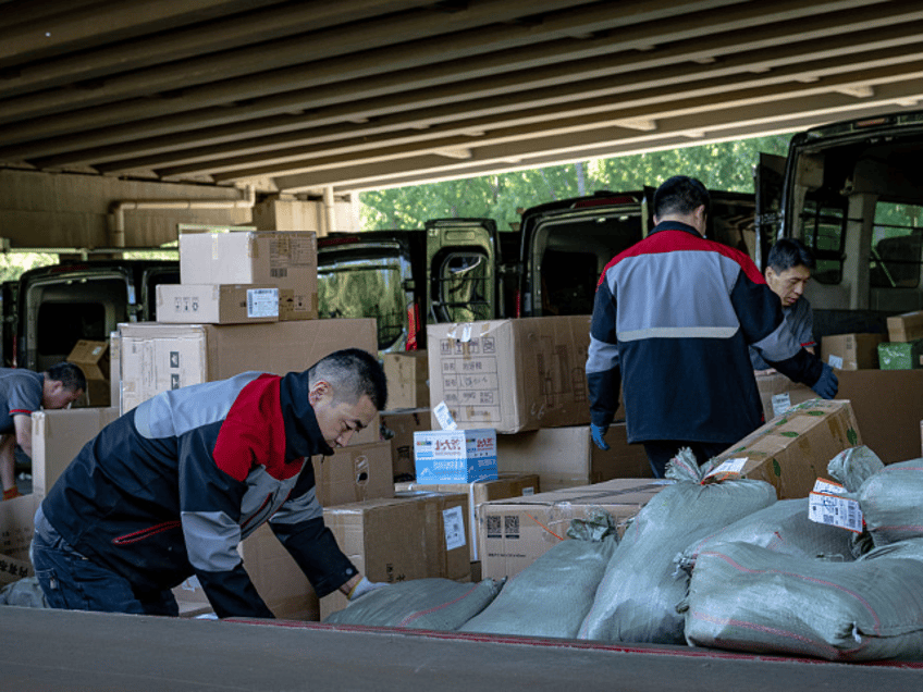 Workers sort packages in front of SF Express vans, operated by SF Holding Co., in Beijing,