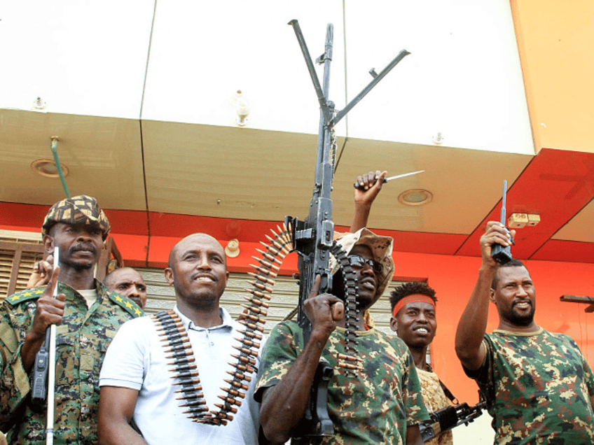 A man poses with Sudanese army soldiers in Salha, south of Omdurman, a day after recapturi