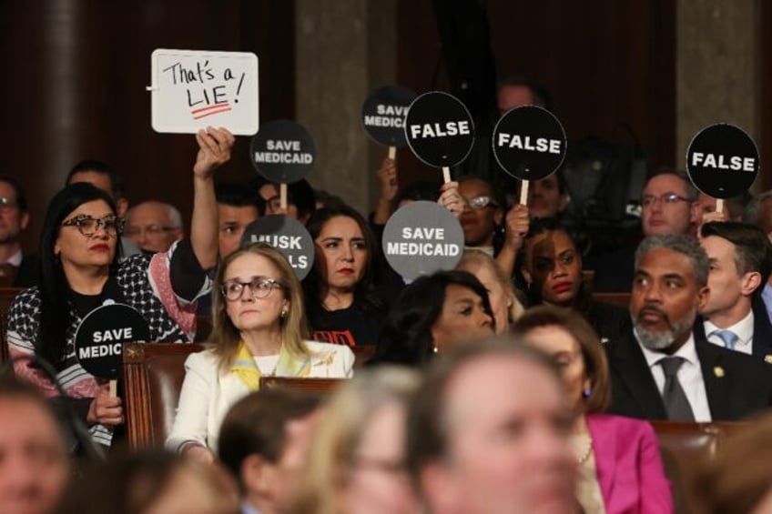 Democrats hold protest signs US President Donald Trump speaks during an address to a joint