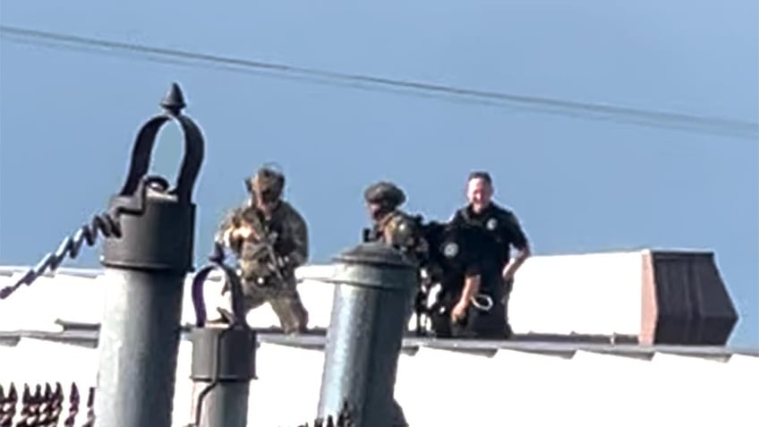 Law enforcement officers stand over the body of would-be Trump assassin, Thomas Crooks on the roof of a building