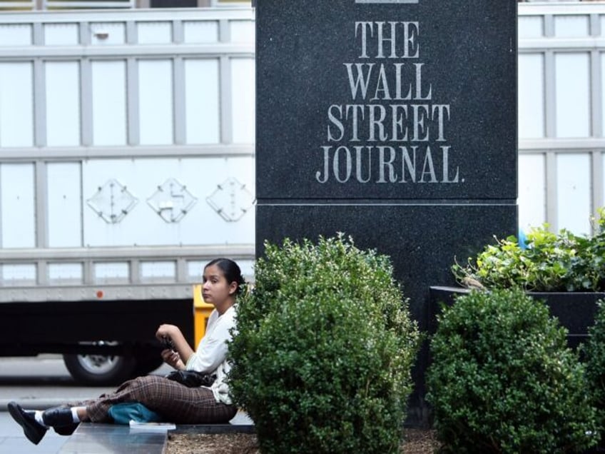 NEW YORK - JULY 31: A woman sits in front of a sign outside a Wall Street Journal office o