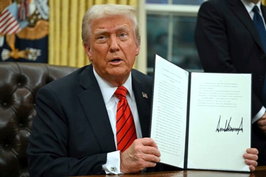 US President Donald Trump signs an executive order in the Oval Office of the White House o
