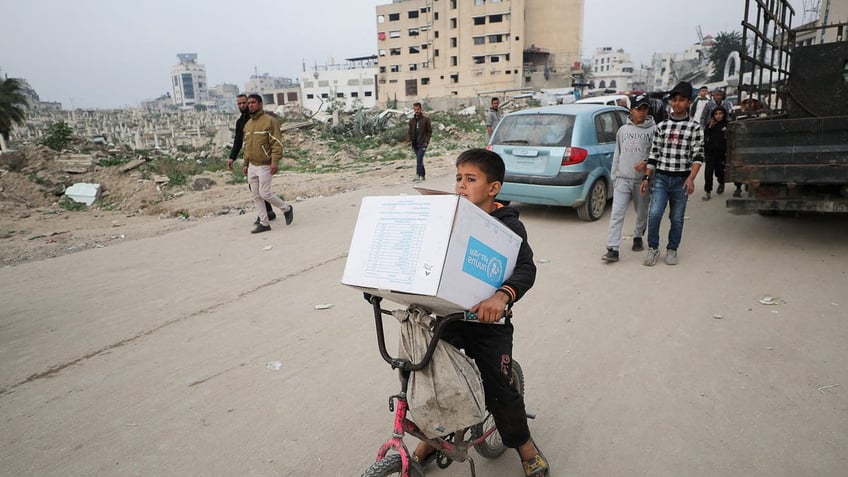 Palestinian child carries UNRWA box on his bike in Gaza City 