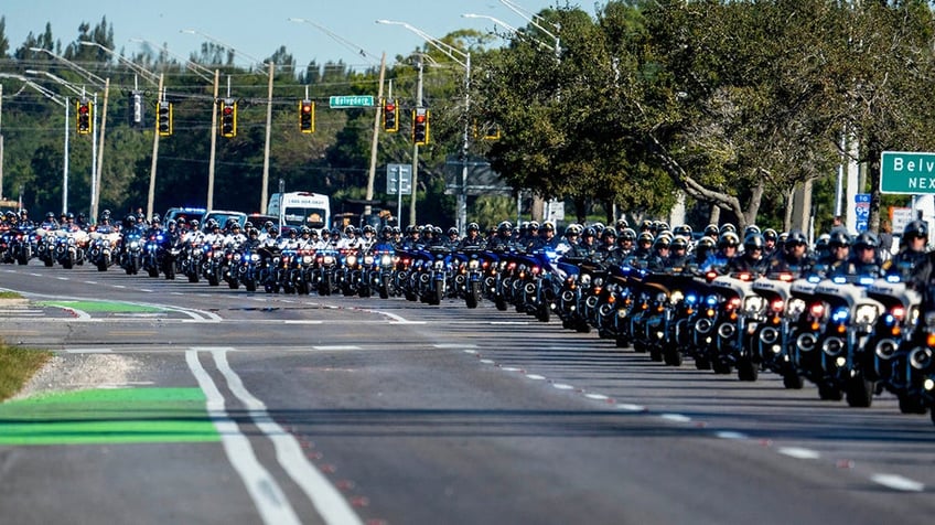 Law enforcement officers ride their motorcycles south along State Road 7 during a procession for three Palm Beach County Sheriff's Office deputies who died last month