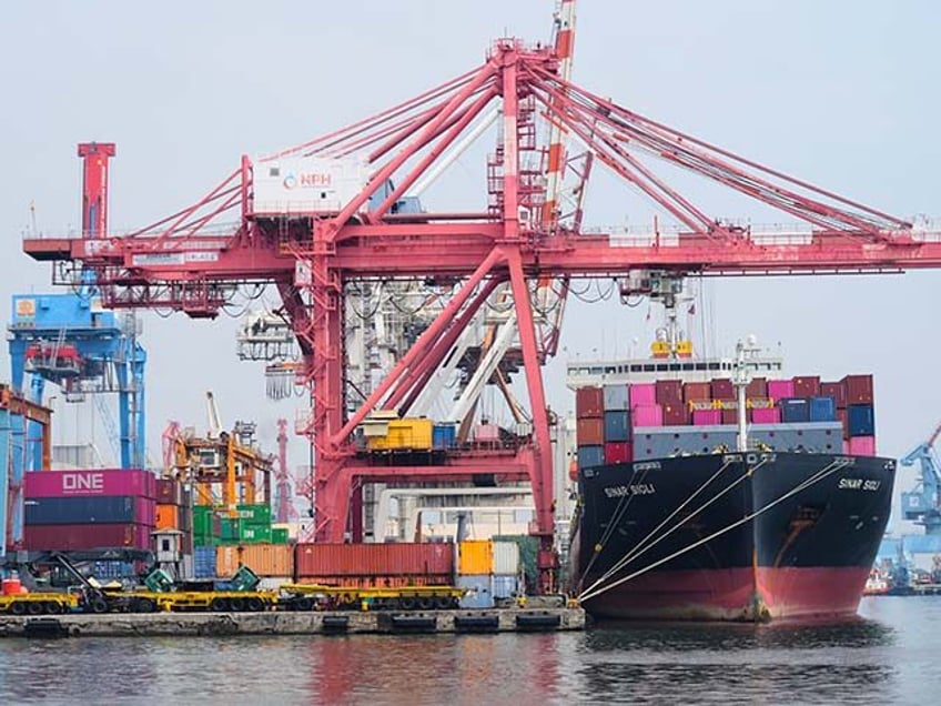 Cranes load shipping containers onto a cargo ship at Jakarta International Container Termi