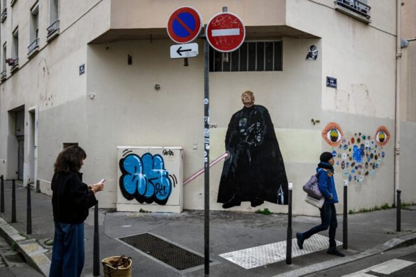 A pedestrian stands next to a graffiti created by French artist Big Ben street Art, depict