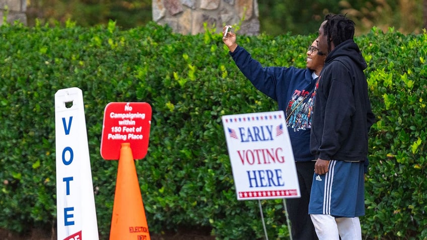 Two voters take a selfie after exiting the polling station, Thursday, Oct. 31, 2024, in Stockbridge, Ga.