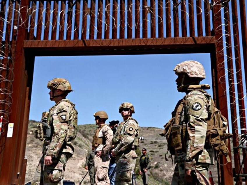 SAN YSIDRO, CA - MARCH 21, 2025 - - Members of the U.S. military are framed by an open ga