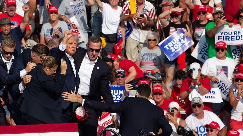 Donald Trump is seen with blood on his face surrounded by secret service