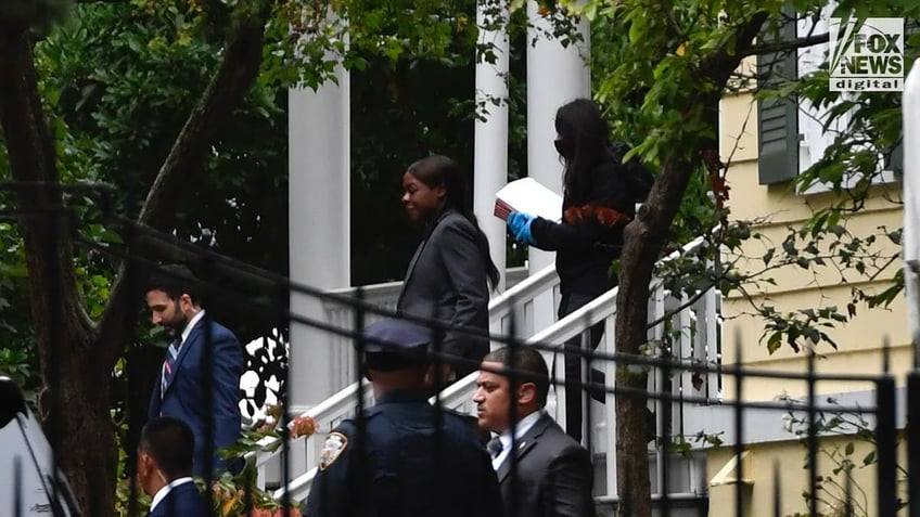 Law enforcement agents leave the New York City Mayor's residence carrying a folder