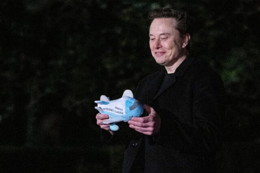 Tesla and SpaceX CEO Elon Musk holds a stuffed Air Force One toy after stepping off Marine