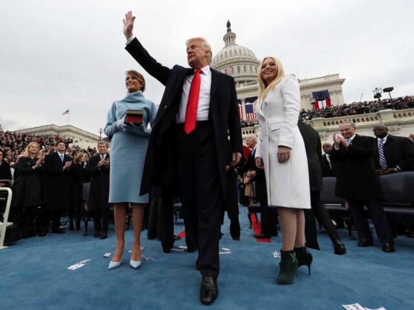 President Donald Trump waves after taking the oath of office as his wife Melania holds the