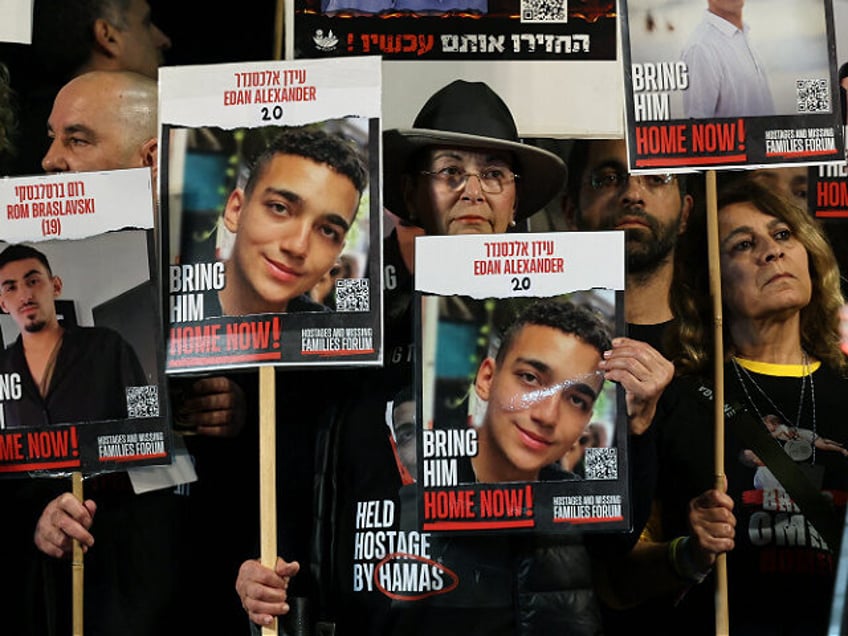 TOPSHOT - Relatives and supporters hold placards bearing portraits of Israeli hostages hel