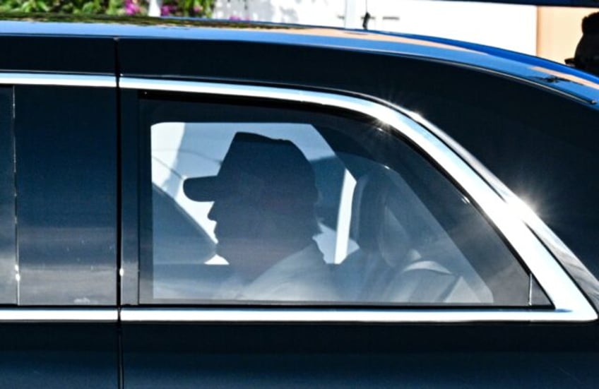 US President Donald Trump rides the back of his presidential limousine as he leaves his So