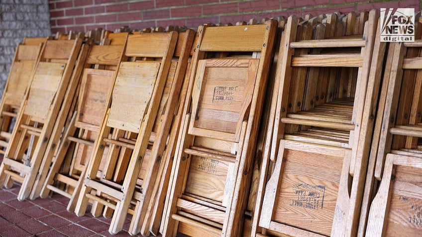 Wooden chairs are folded up against a wall