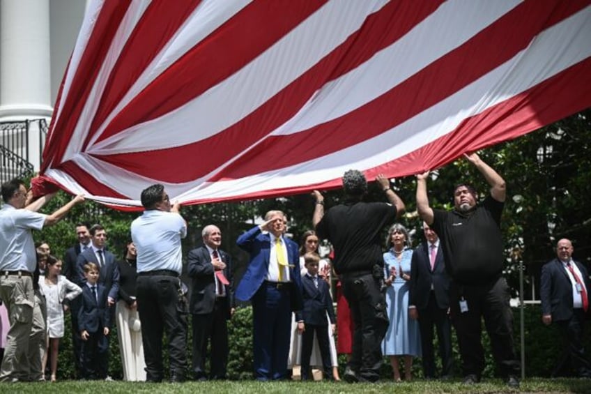 US President Donald Trump salutes as a US flag is raised on a newly installed flagpole on