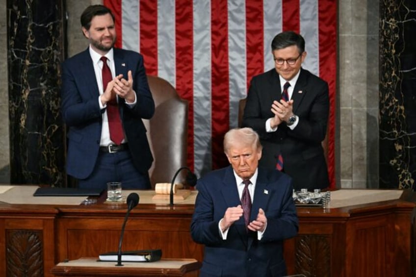 US President Donald Trump stands and applauds as he concludes his address to a joint sessi