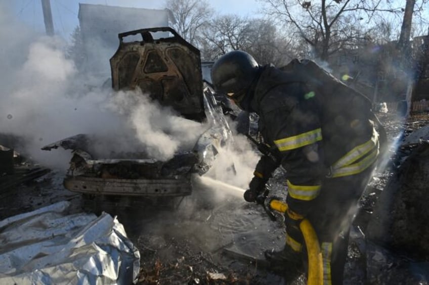 A firefighter extinguishes a burning car at a site of a Russian strike in Kharkiv