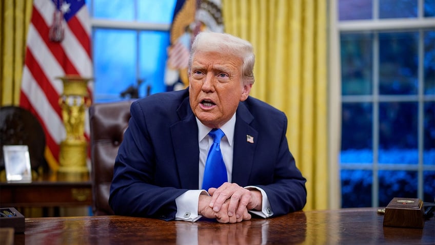 President Donald Trump sits at the Resolute Desk in the Oval Office