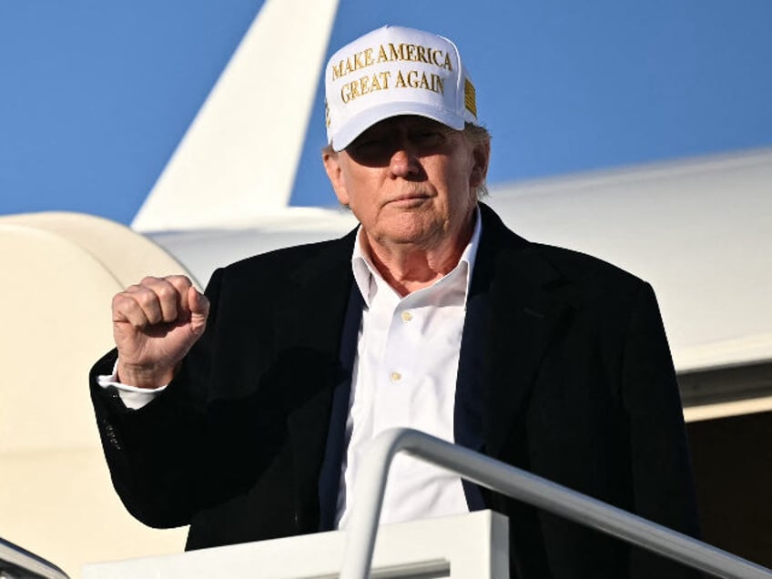 US President Donald Trump raises a fist as he steps off Air Force One upon arrival at Join