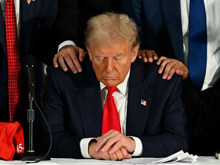 TOPSHOT - Former US President and Republican presidential candidate Donald Trump prays dur