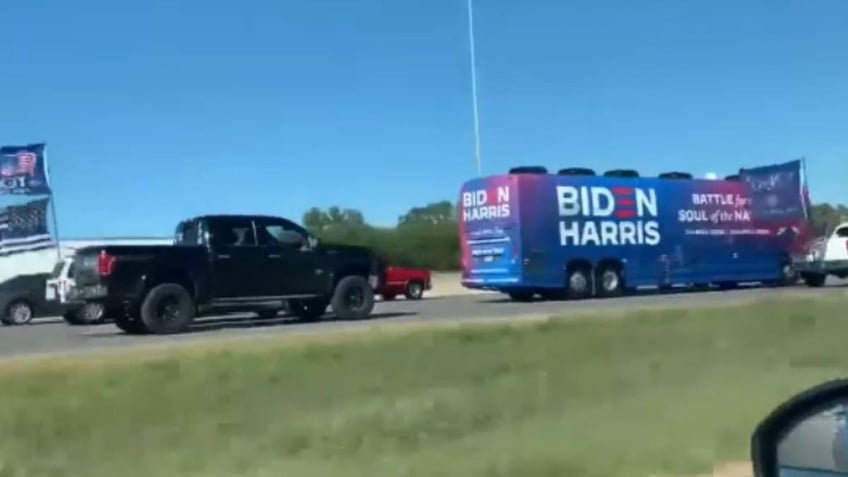 A Trump supporter in a pick-up truck tails a Biden-Harris campaign bus in 2020