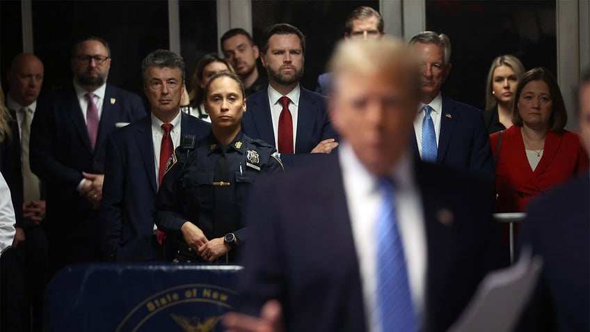 Trump supporters in background, blurry Donald Trump in foreground