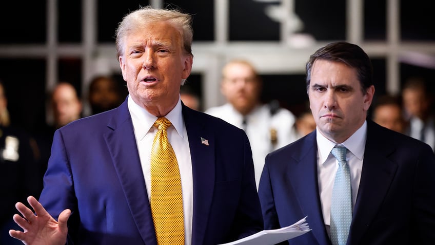 Trump speaks outside court in blue coat, yellow tie