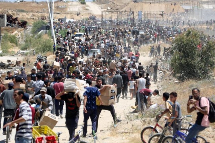 People carry boxes of relief supplies from the Gaza Humanitarian Foundation at adistributi